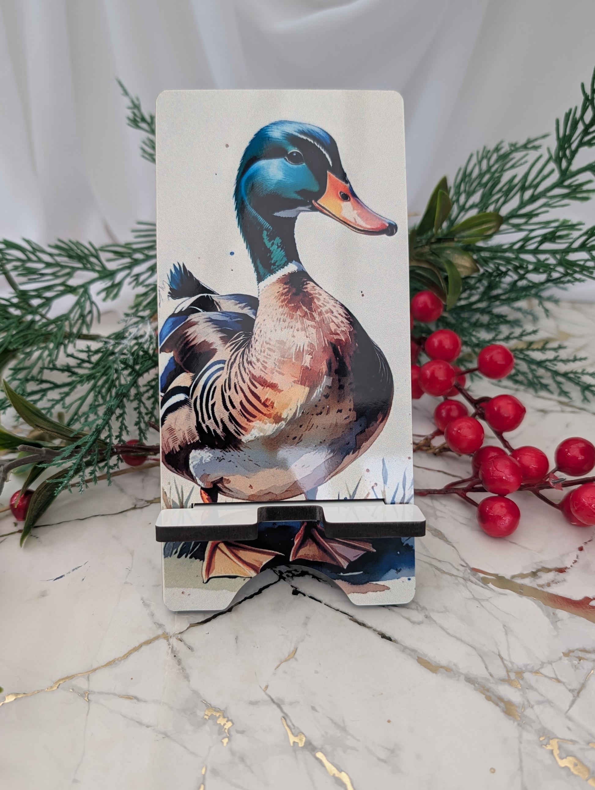 Phone stand with duck design on a marble surface with greenery and berries