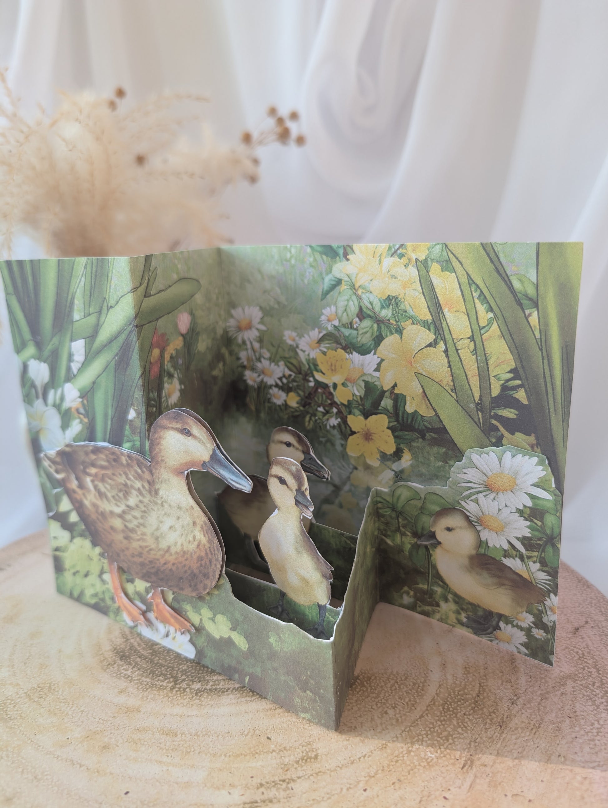 Greeting card with ducks and flowers on a wooden surface