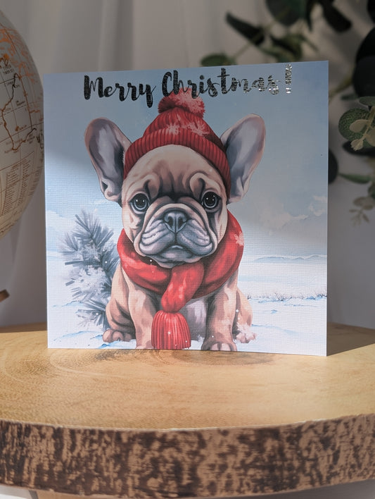 French Bulldog Christmas Card - tan French Bulldog in the snow wearing a red woollie hat and scarf.  Merry Christmas in foiled lettering