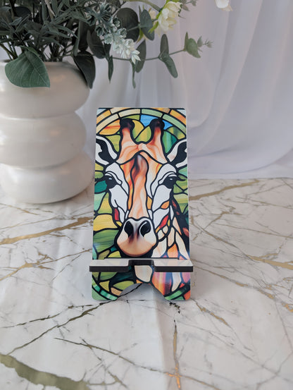 Colorful giraffe gift - stained glass style design on a mobile phone stand with a white vase and plant in the background.