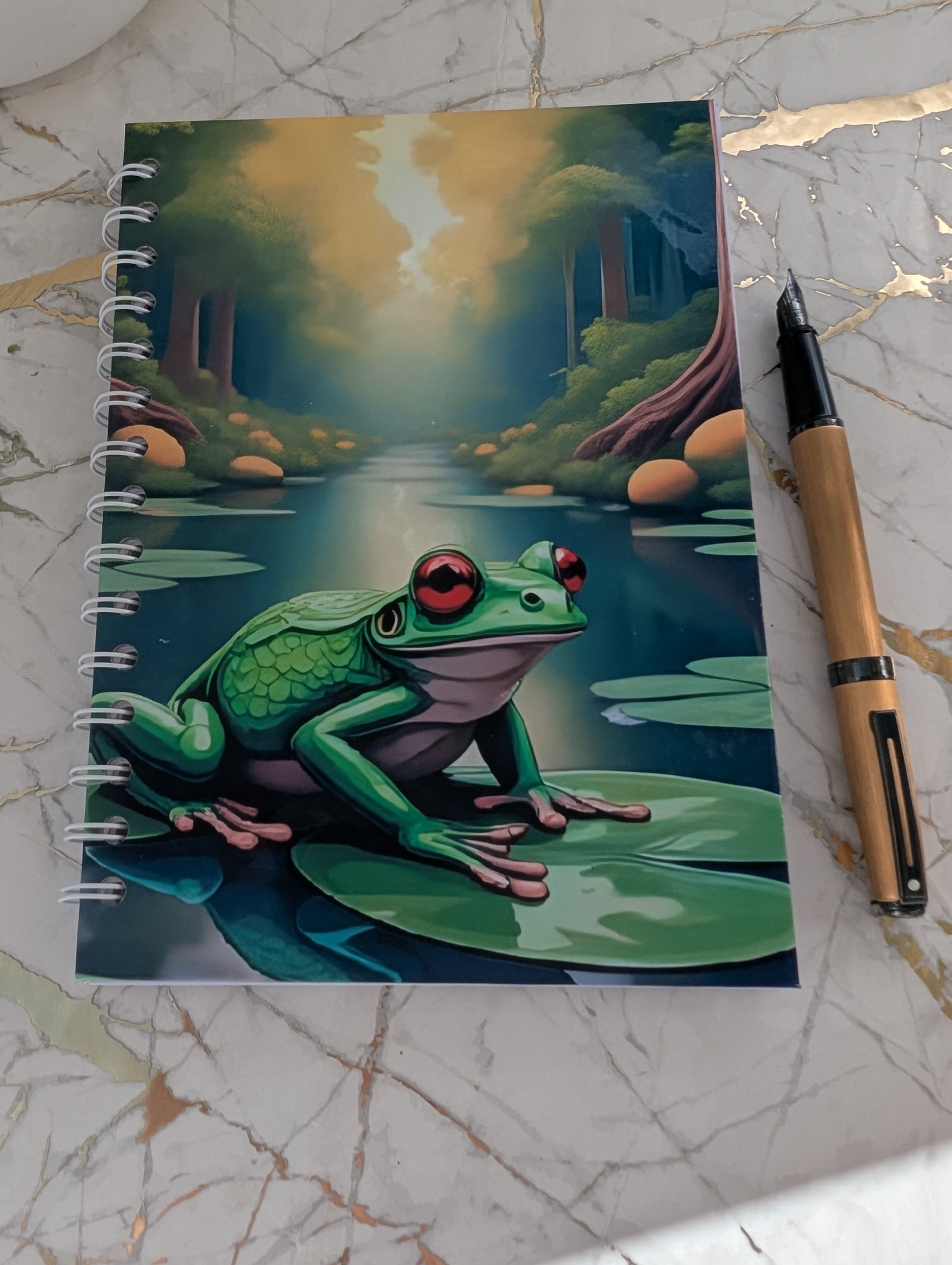 Close up of a handmade, glossy hardback cover notebook, featuring a colourful frog on a lilypad design