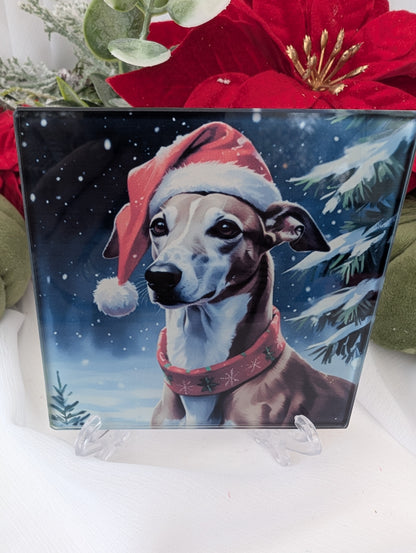 Greyhound Gifts - handsome greyhound Christmas Coaster.  he is wearing a Santa hat and Christmas sweater against a snowy background.