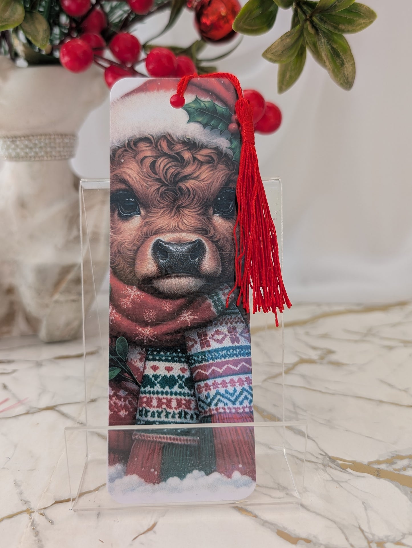 Bookmark with a cow wearing a Christmas sweater and hat on a decorative background