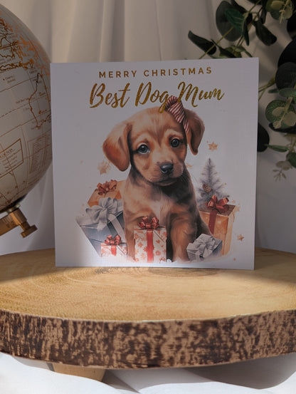 Labrador Christmas card with puppy and  'Merry Christmas Best Dog Mum' text on a wooden surface.