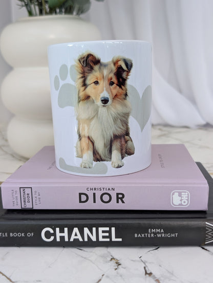White ceramic Border Collie mug, with watercolour style image of Border collie against a background of soft grey hearts, pawprints and bones