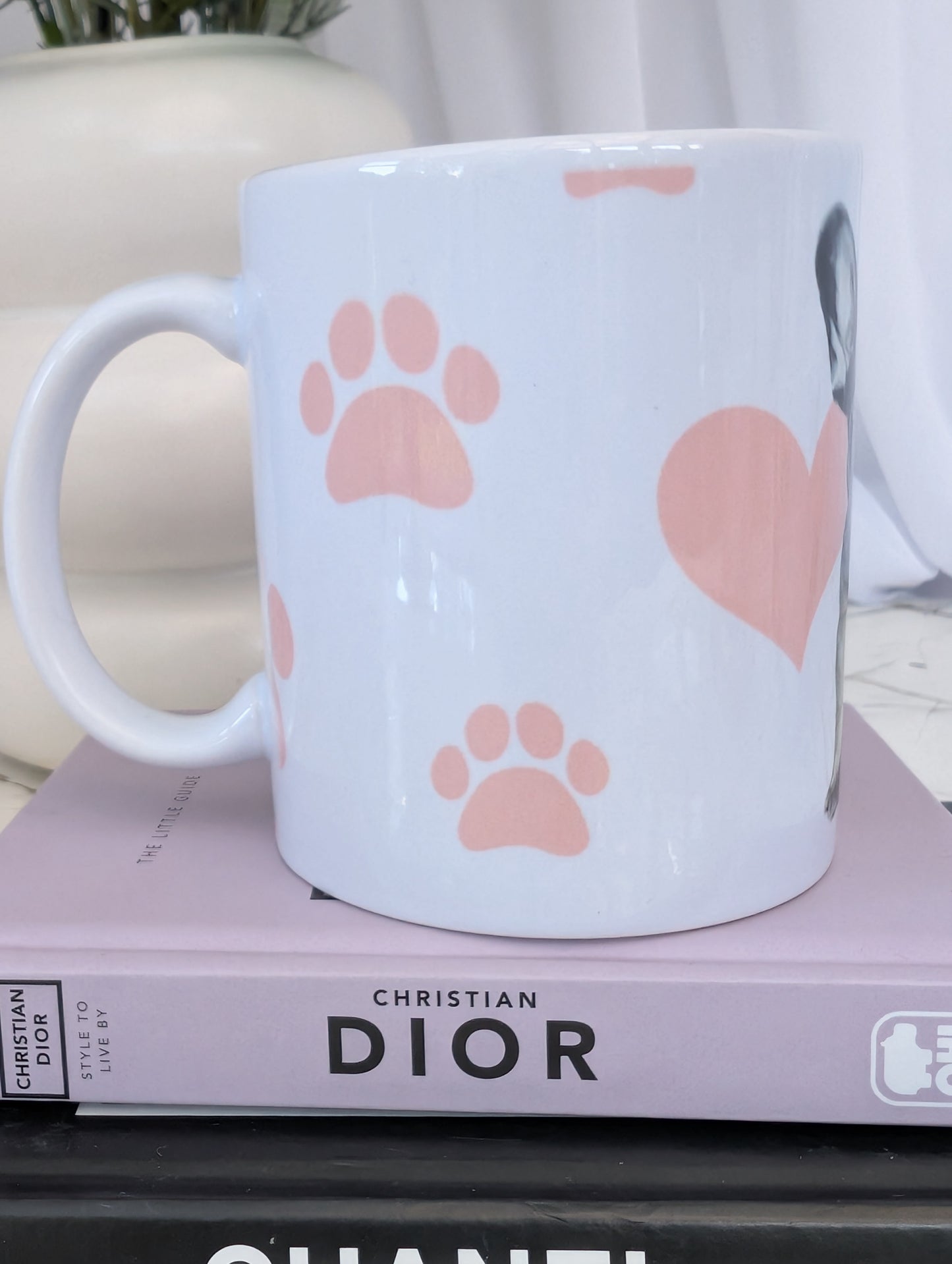Right side view of white ceramic 11oz French Bulldog mug on a background of pink hearts, paws and bones