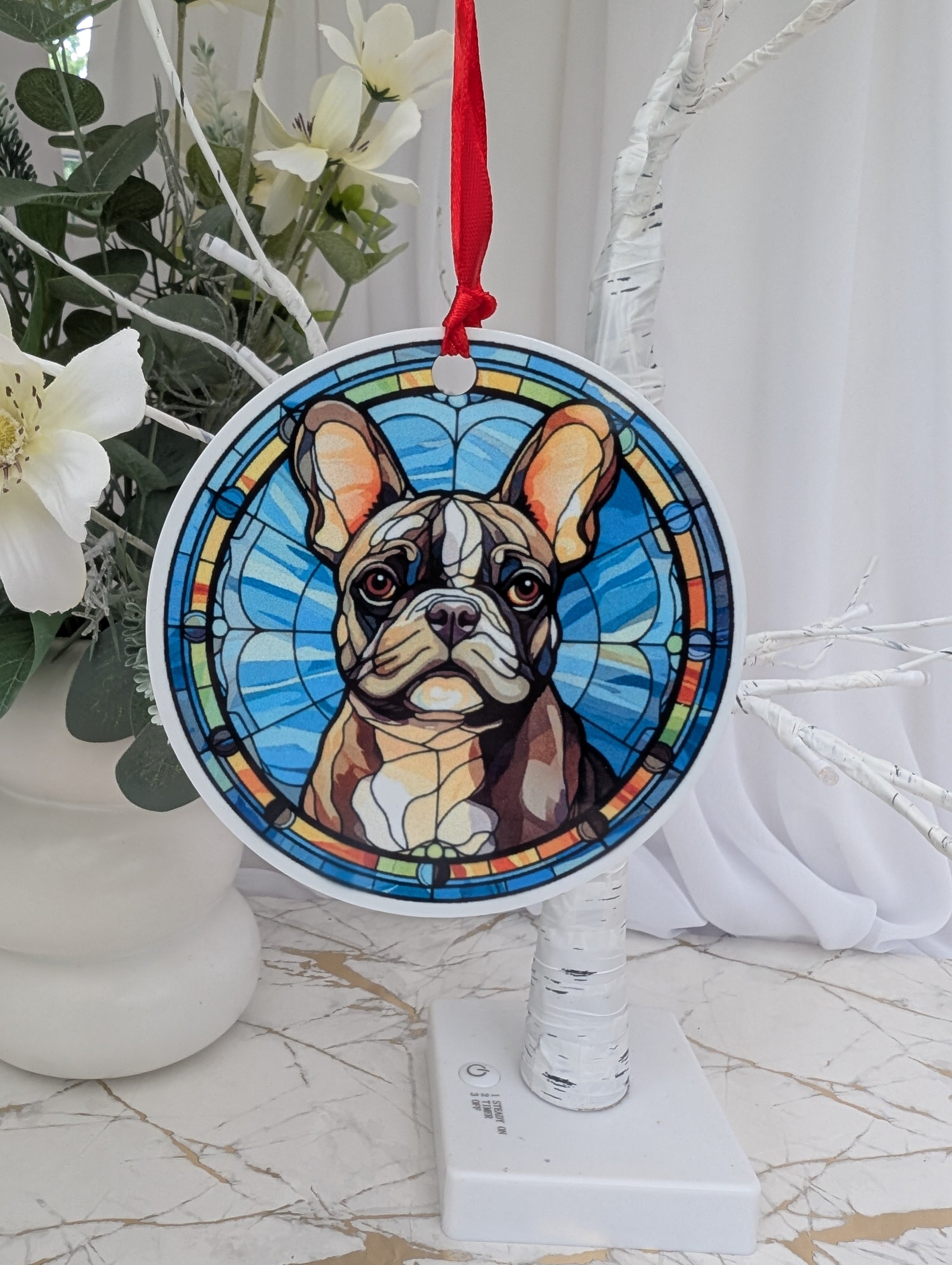Round, aluminium, stained glass style French bulldog hanging ornament hanging on a white tree branch 