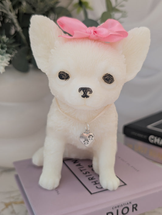 Close-up of lifelike wax Chihuahua candle with charm around neck and on head, showing fine facial features and realistic wax fur texture