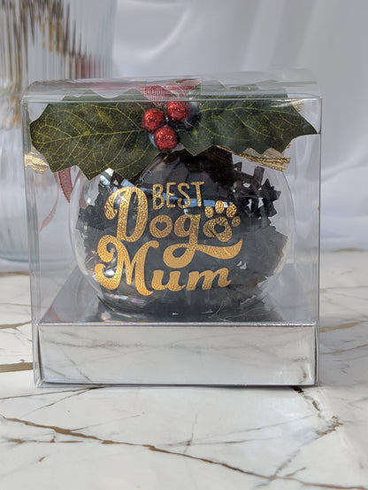Decorative Christmas ball with 'Best Dog Mum' text in a clear gift box on a marble surface.
