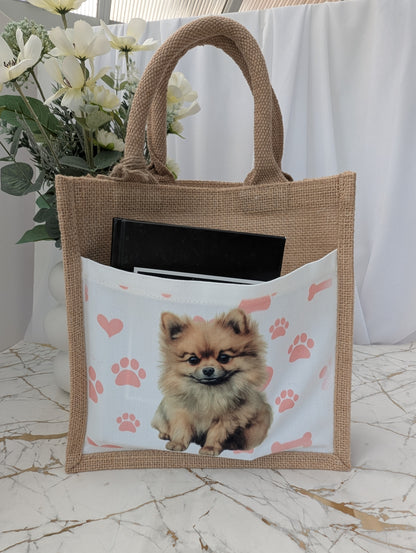  eco friendly jute tote bag with cream front pocket printed with Pomeranian dog and background of pink pawprint, hearts and bones - showing book in the pocket