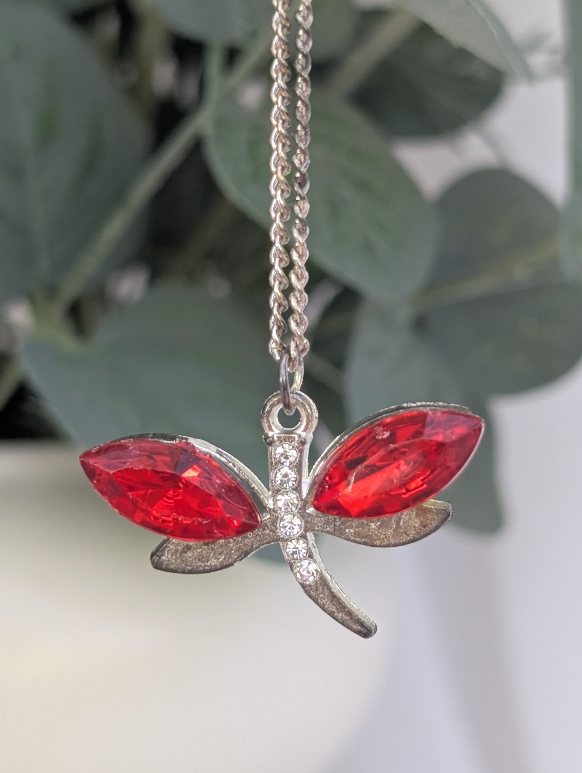 Front view of silver tone dragonfly pendant with red crystal stone wings and clear diamante stone accents
