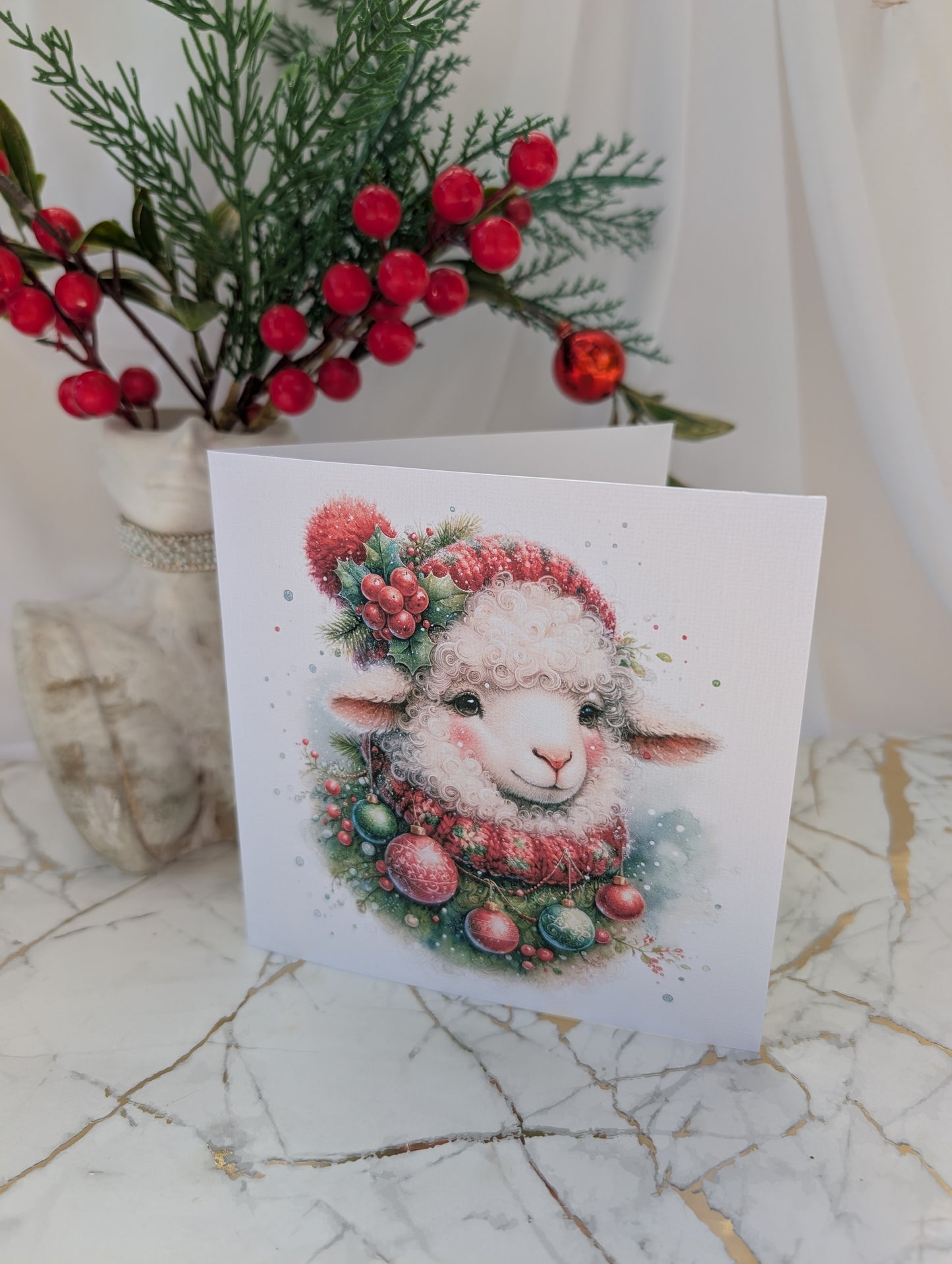 Sheep Christmas Card - wearing red bobble hat and scarf adorned with Christmas baubles printed on 300gsm linen effect card