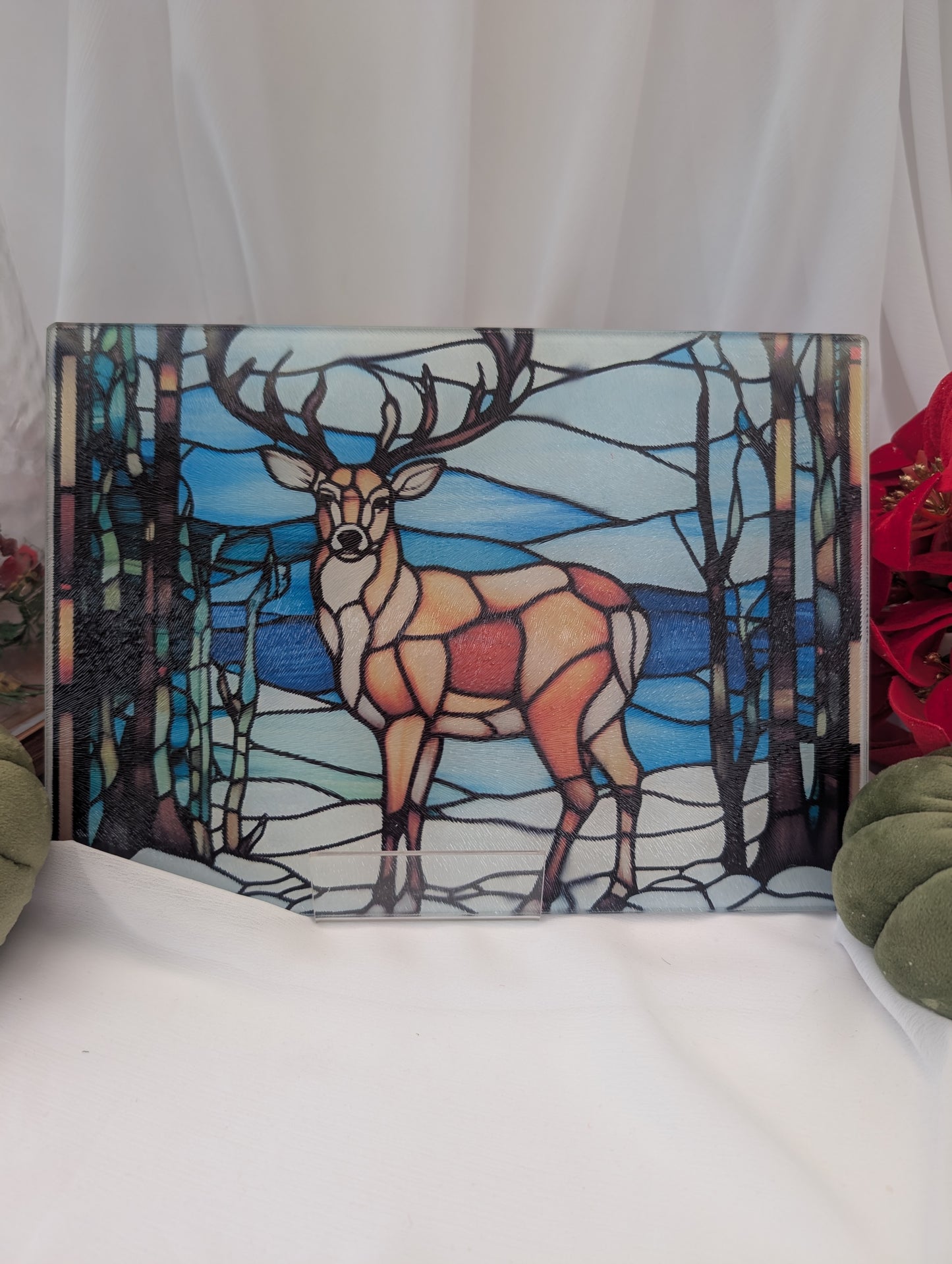 Stained glass worktop saver with a stag in a forest scene on a white surface.