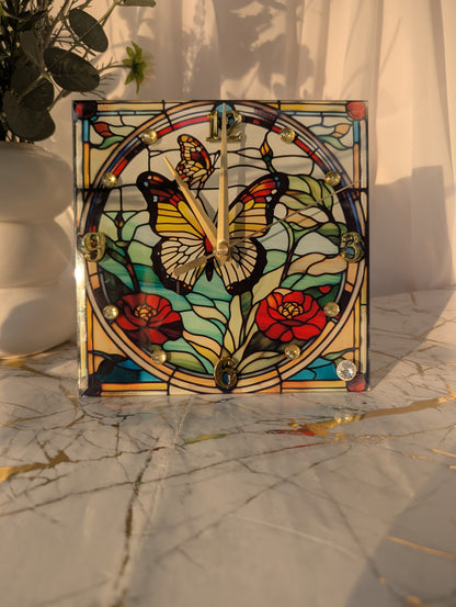 Butterfly clock in natural light on a shelf, highlighting multicolour stained glass-style effect and gold clock hands.