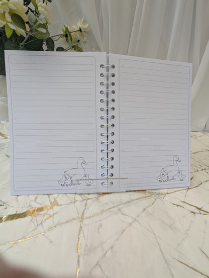 Open view of the inside pages of a duck, faux stained-glass style glossy notebook, 120gsm luxury paper hand printed with duck line drawing in the right hand colour.