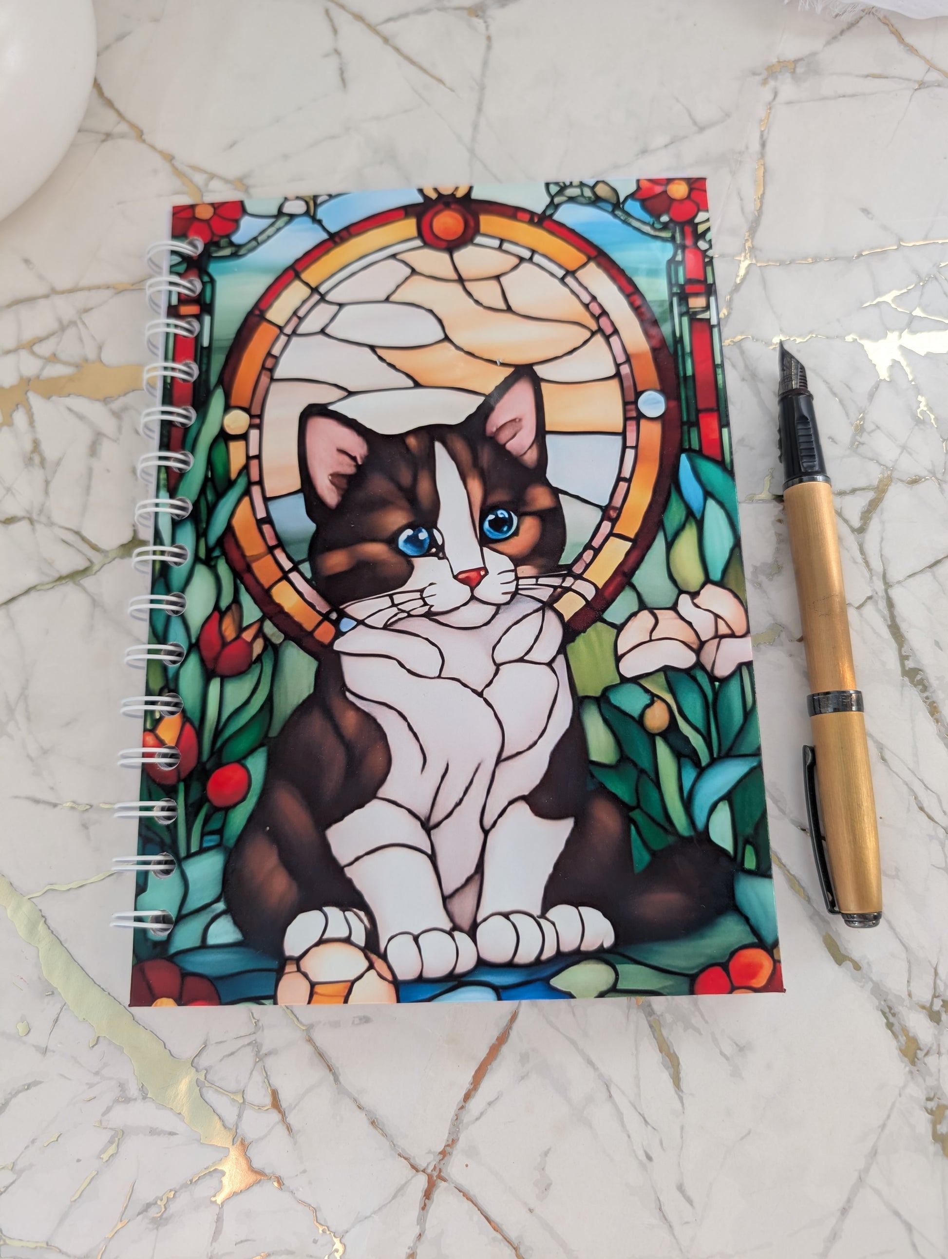 Top view of quirky and colourful kitten notebook.  Stained glass design, A5 size hardback
