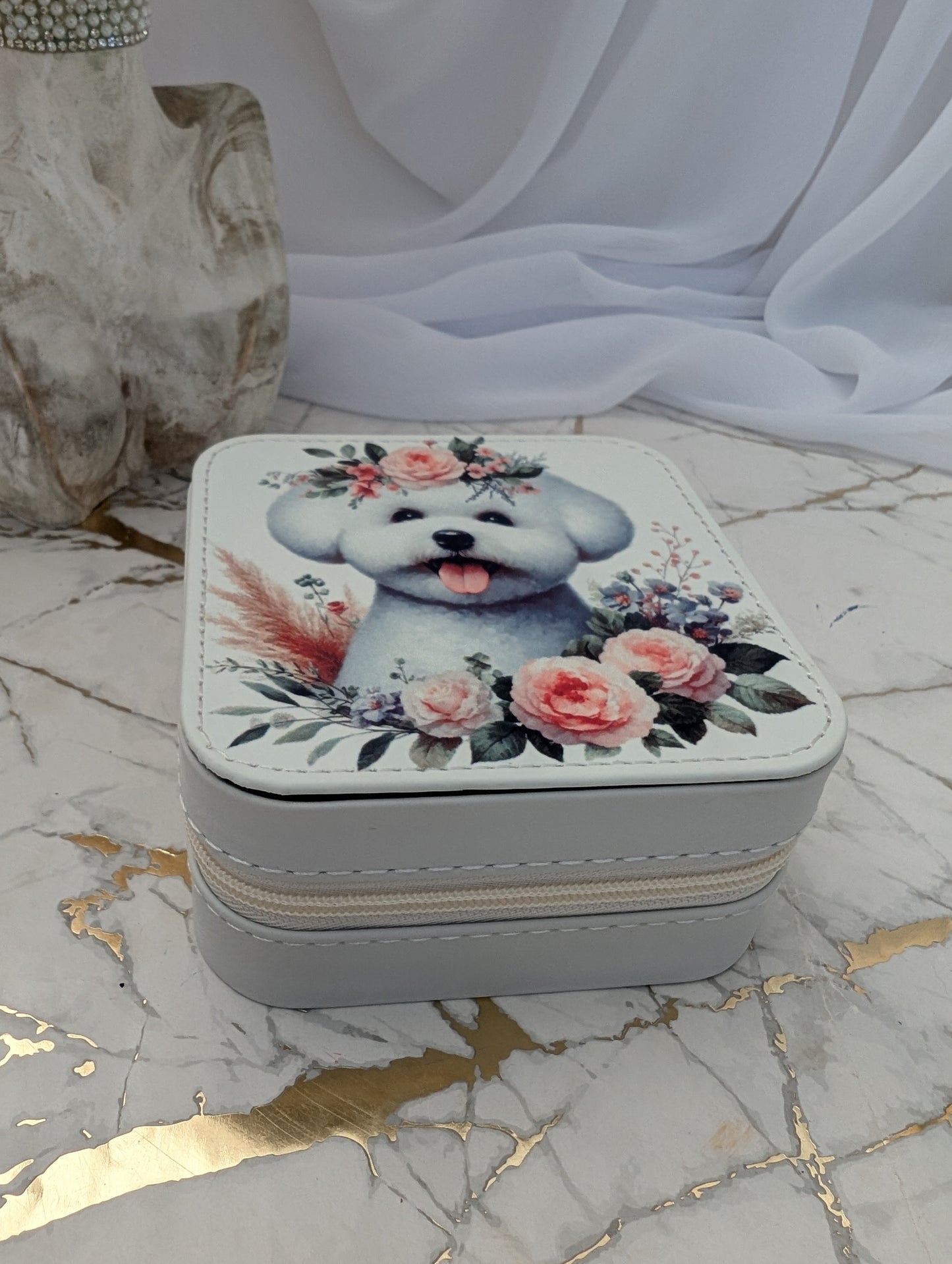 Small square jewelry box with a Bichon Frise and floral design on a marble surface.