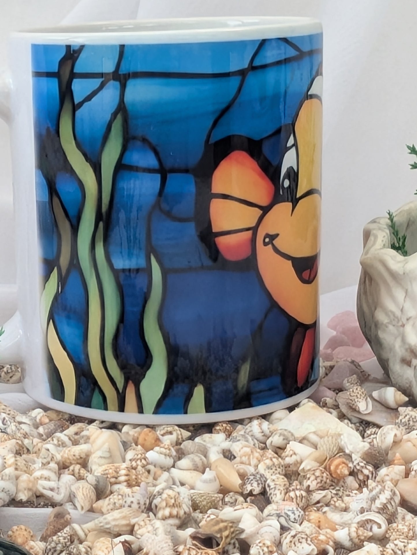 Mug with cartoon character design on a bed of seashells