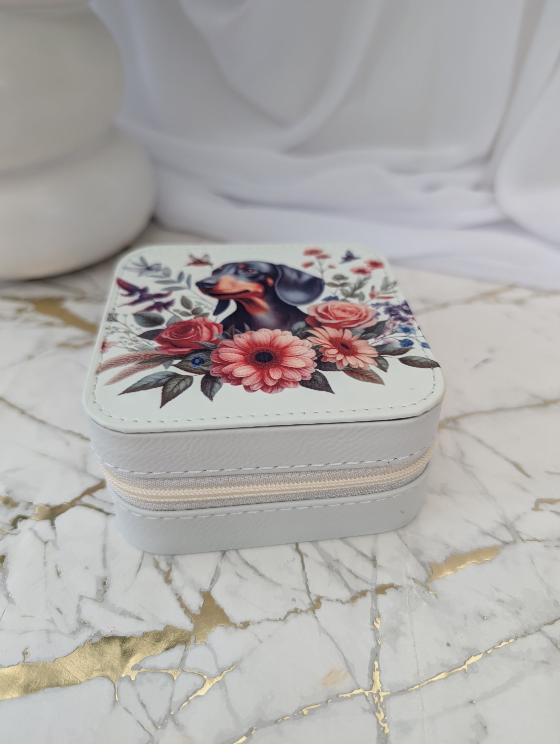 Jewelry box with floral design and dachshund on a marble surface