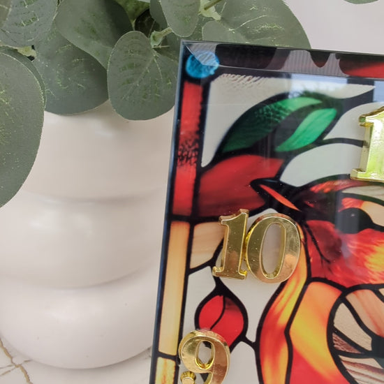 Video of robin clock turning slowly to show stained glass-style details and freestanding design.