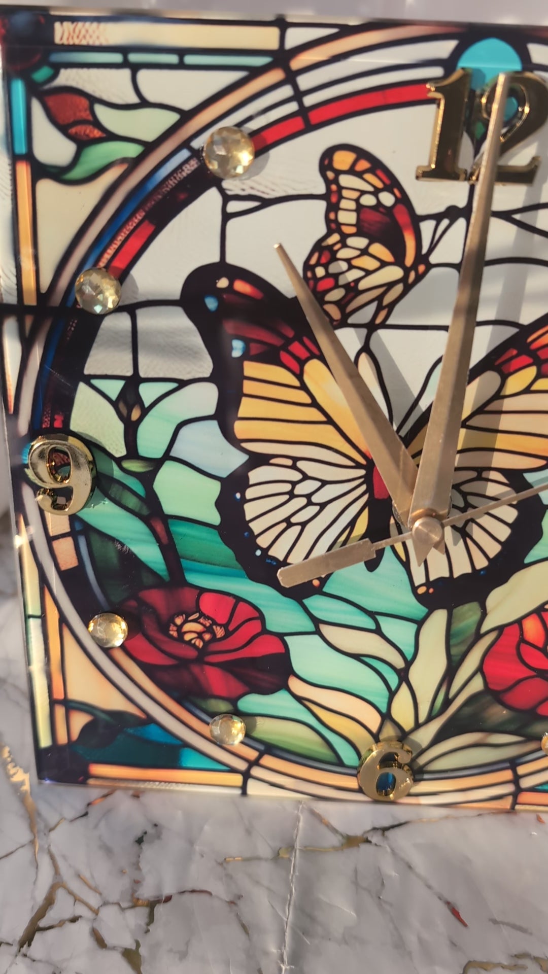 stained glass-style butterfly clock slowly rotating to display its vivid colours and freestanding design.