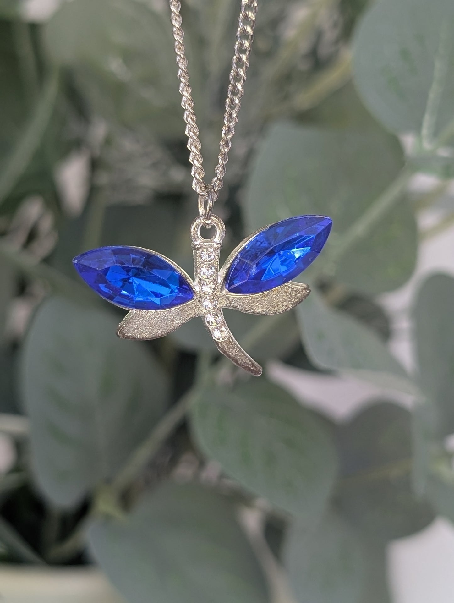 mid shot of silver tone dragonfly necklace with sapphire blue colour crystal wings and clear diamante body accents